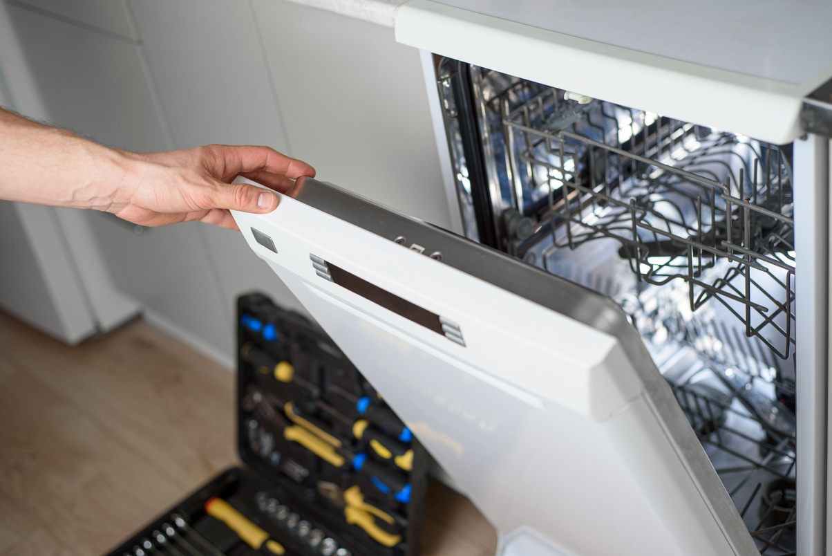 Man repairing a dishwasher with tools